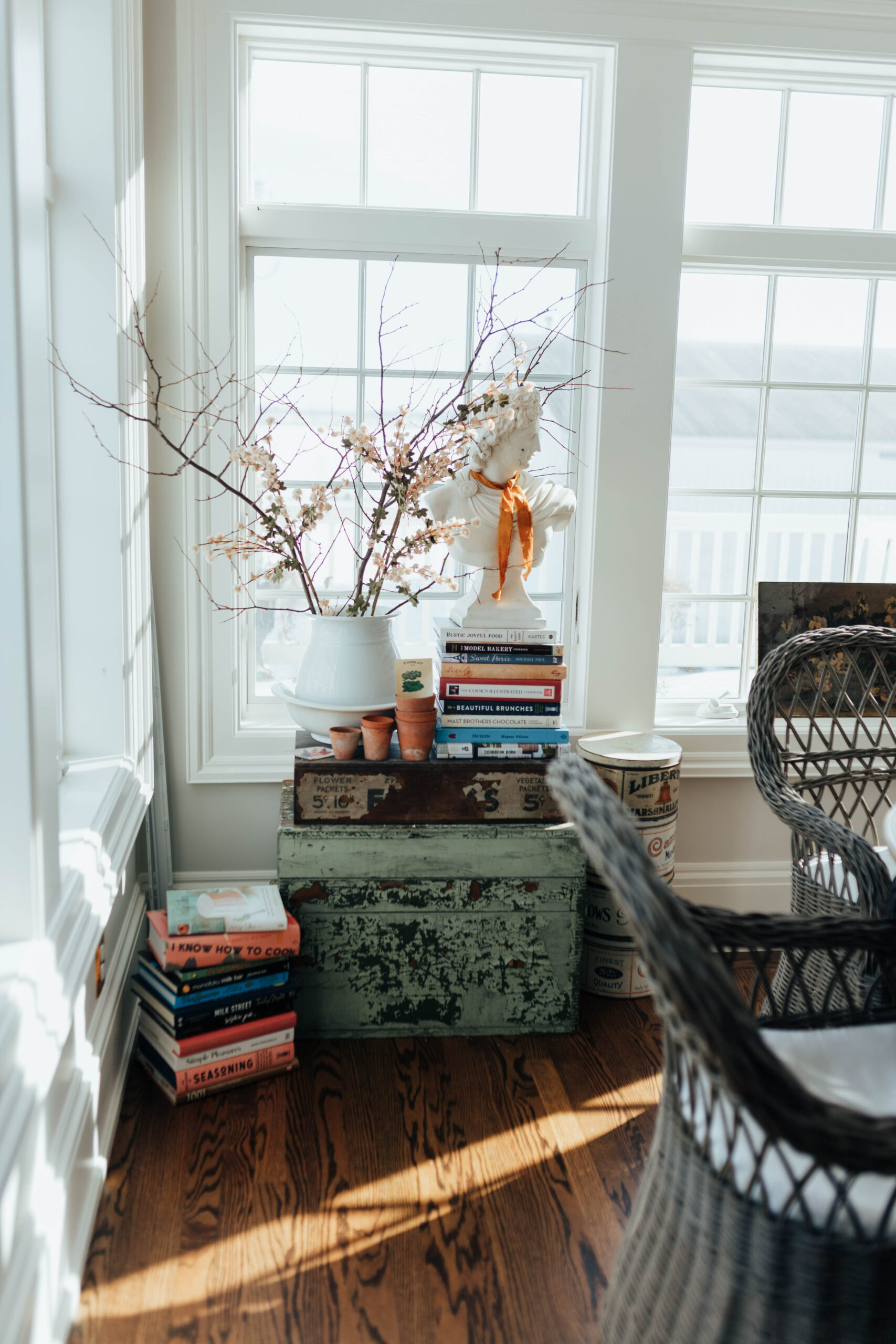 Pile of cookbooks with vintage seed display and fresh spring twigs and large antique bust